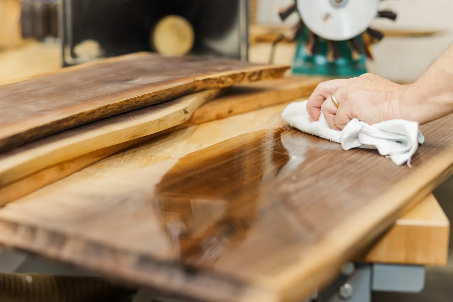 A person polishing a wooden table with a cloth.