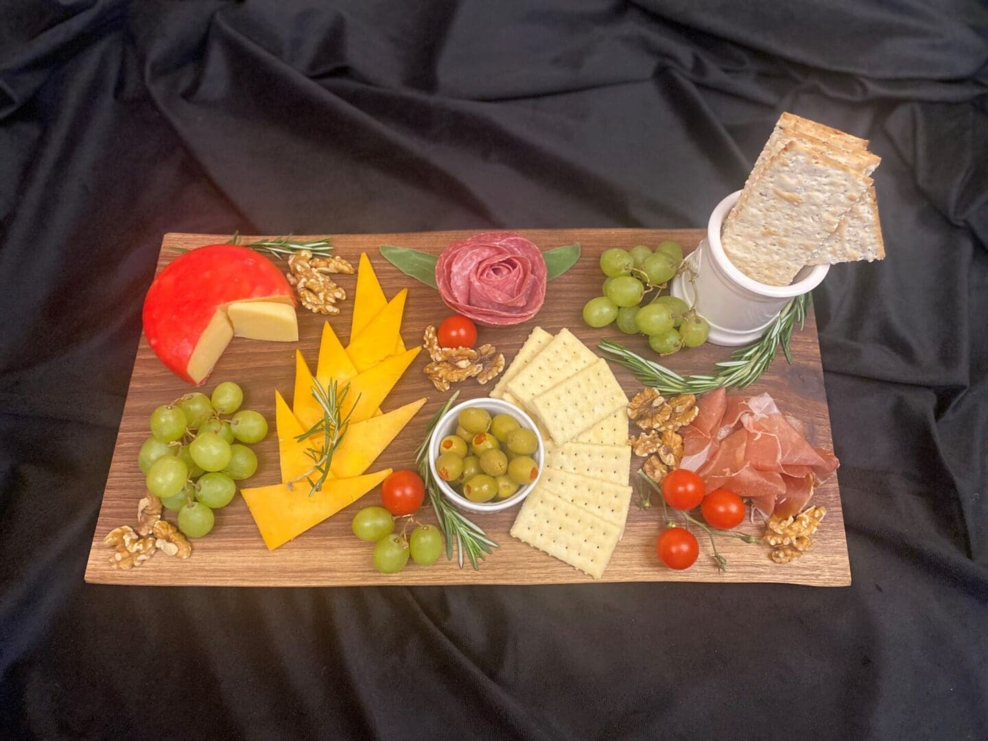 Cheese board with fruits, crackers, and meats.