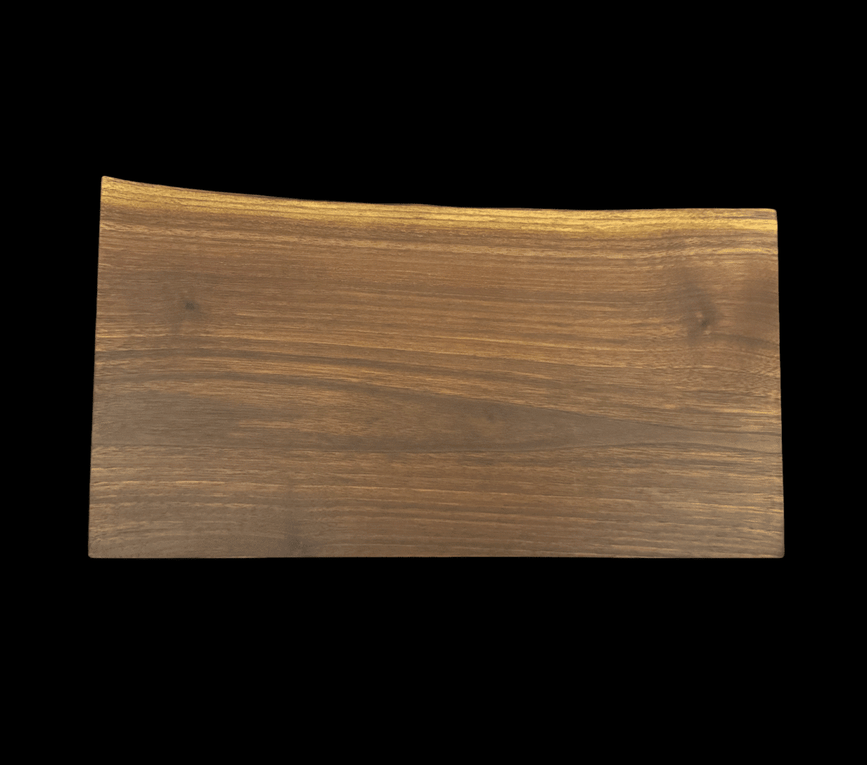 Curved wooden cutting board on dark background.